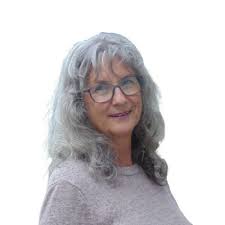 Photograph of a woman with long wavy silver hair and glasses smiling at the camera.