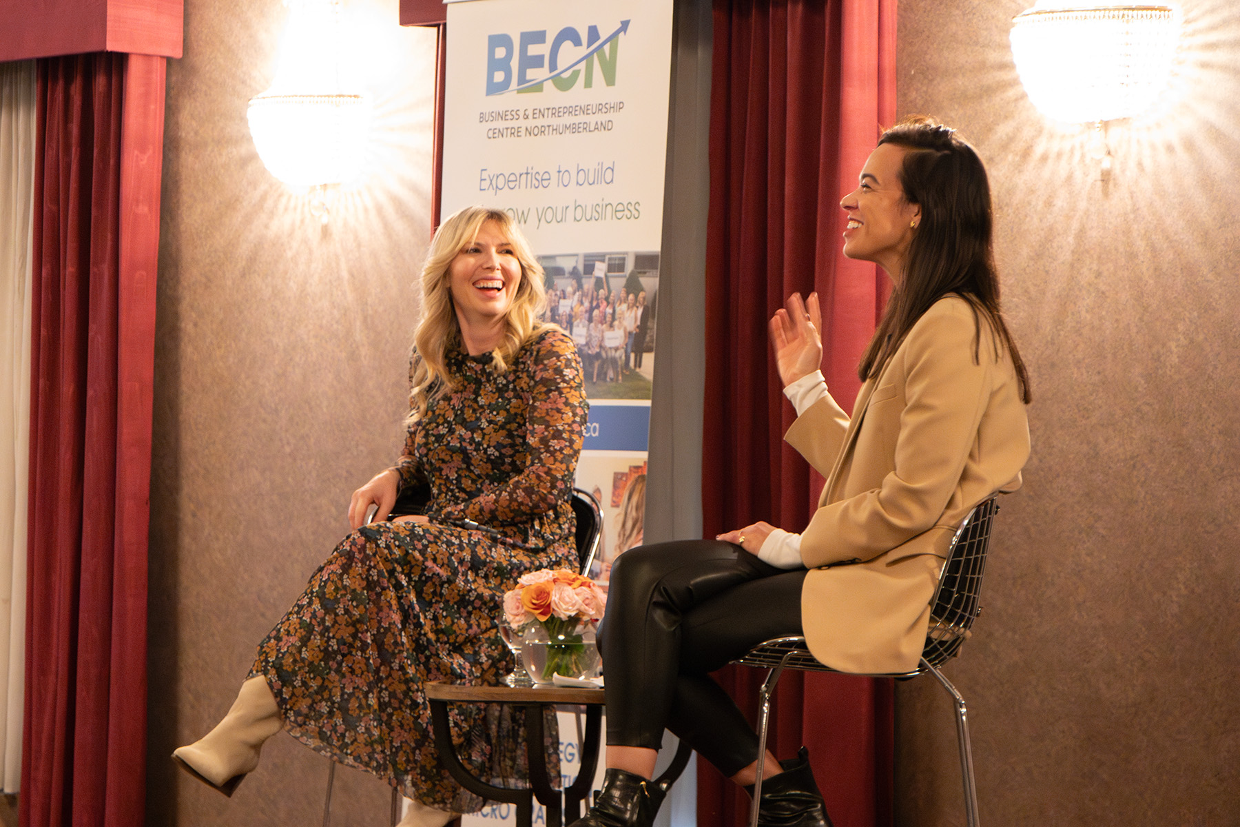 Two presenters sitting on stage at a BECN Conference.