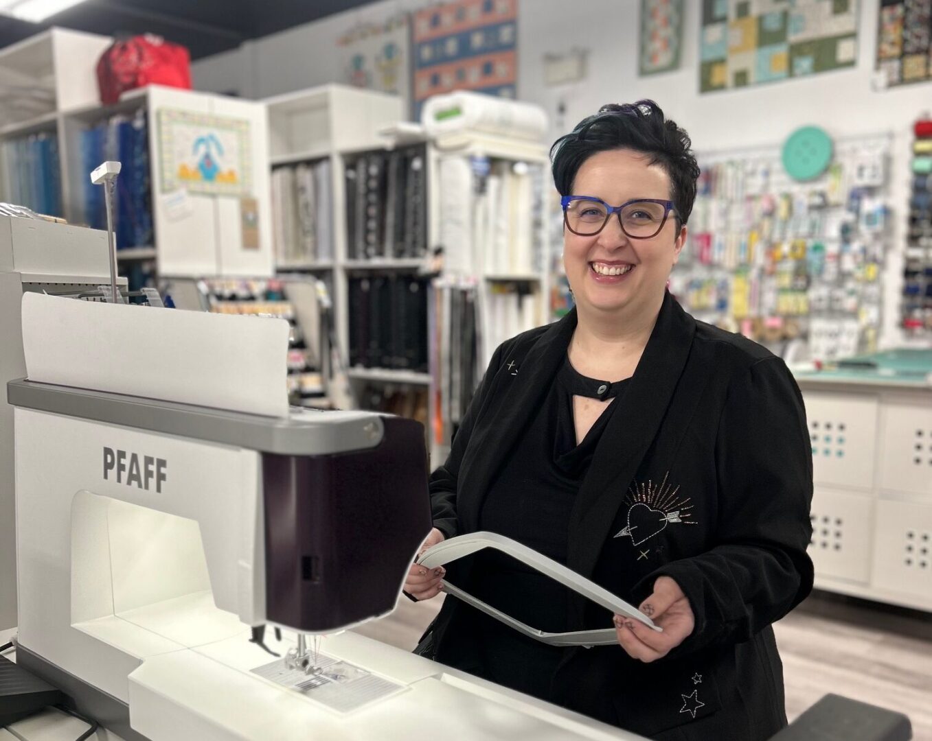 Embellish business owner smiles behind sewing machine