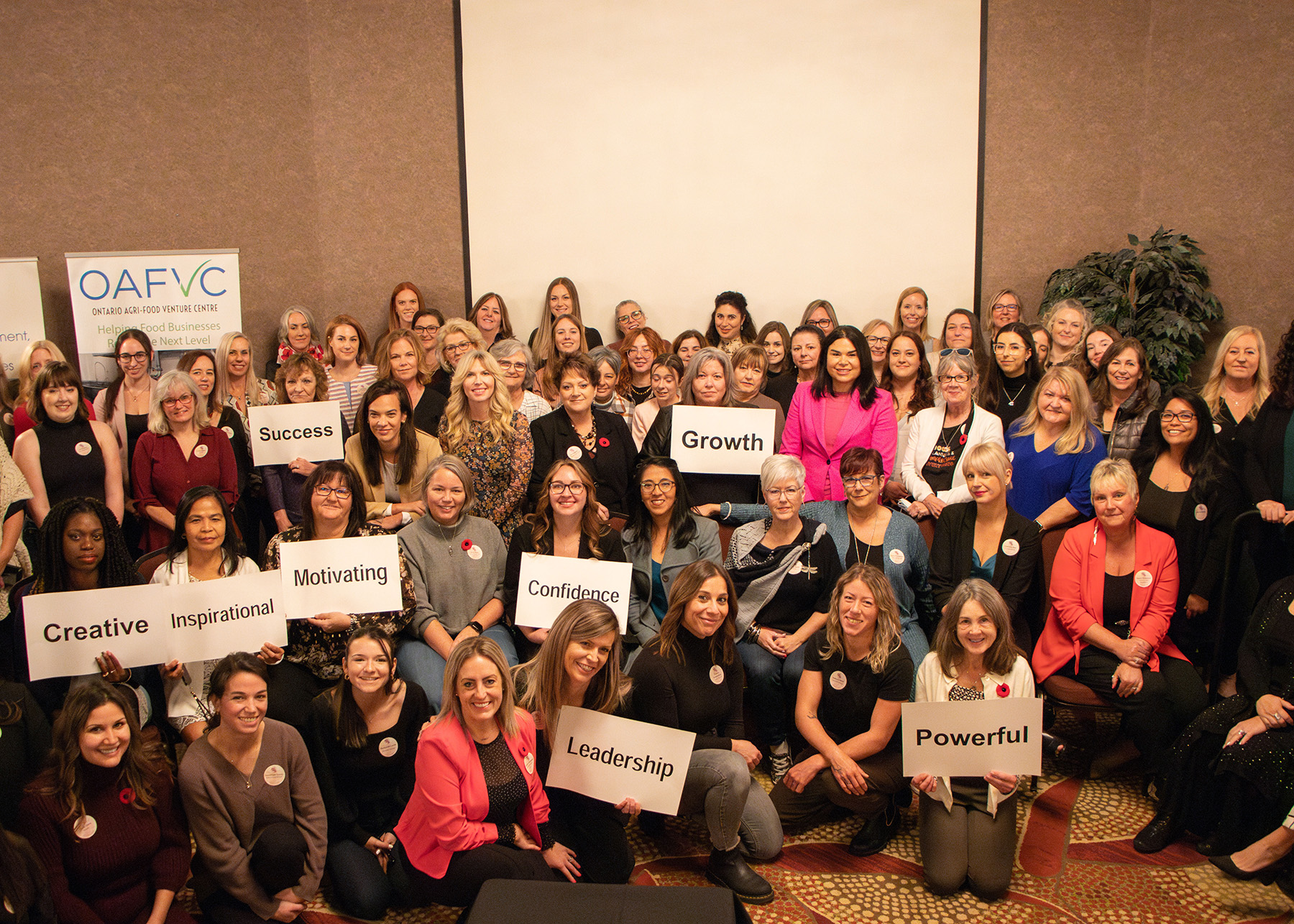 Group of participants holding signs at the She Owns It Conference