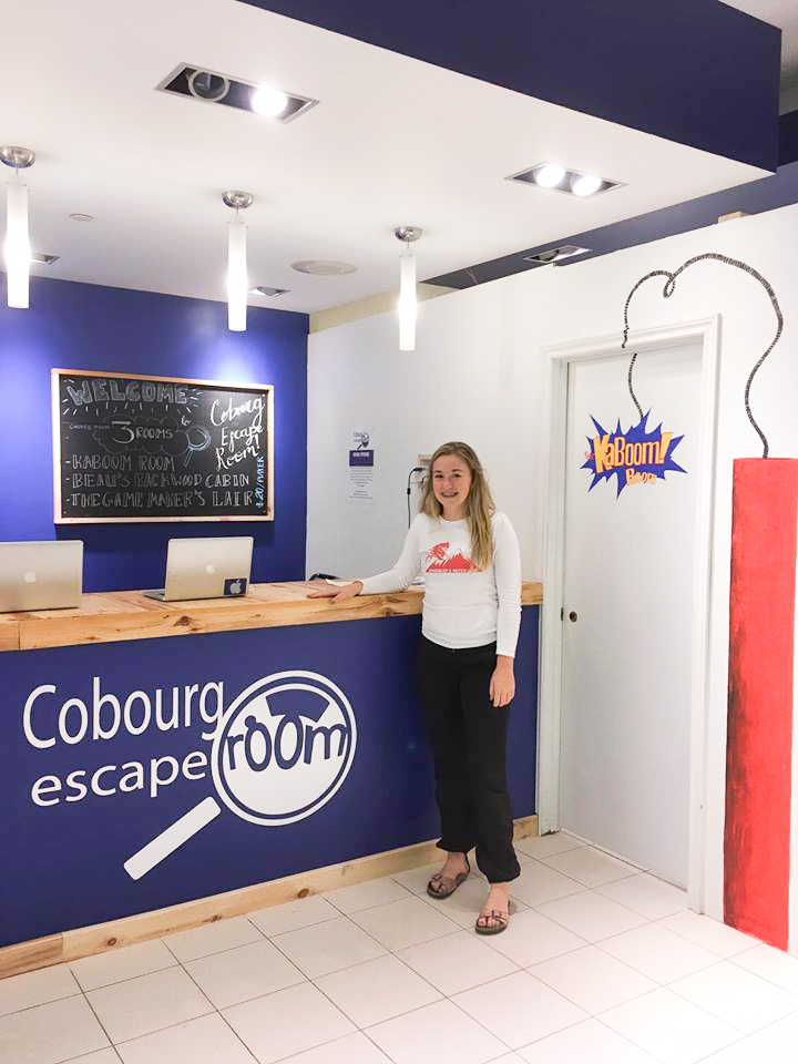 Business owner poses next to Cobourg Escape Room sign