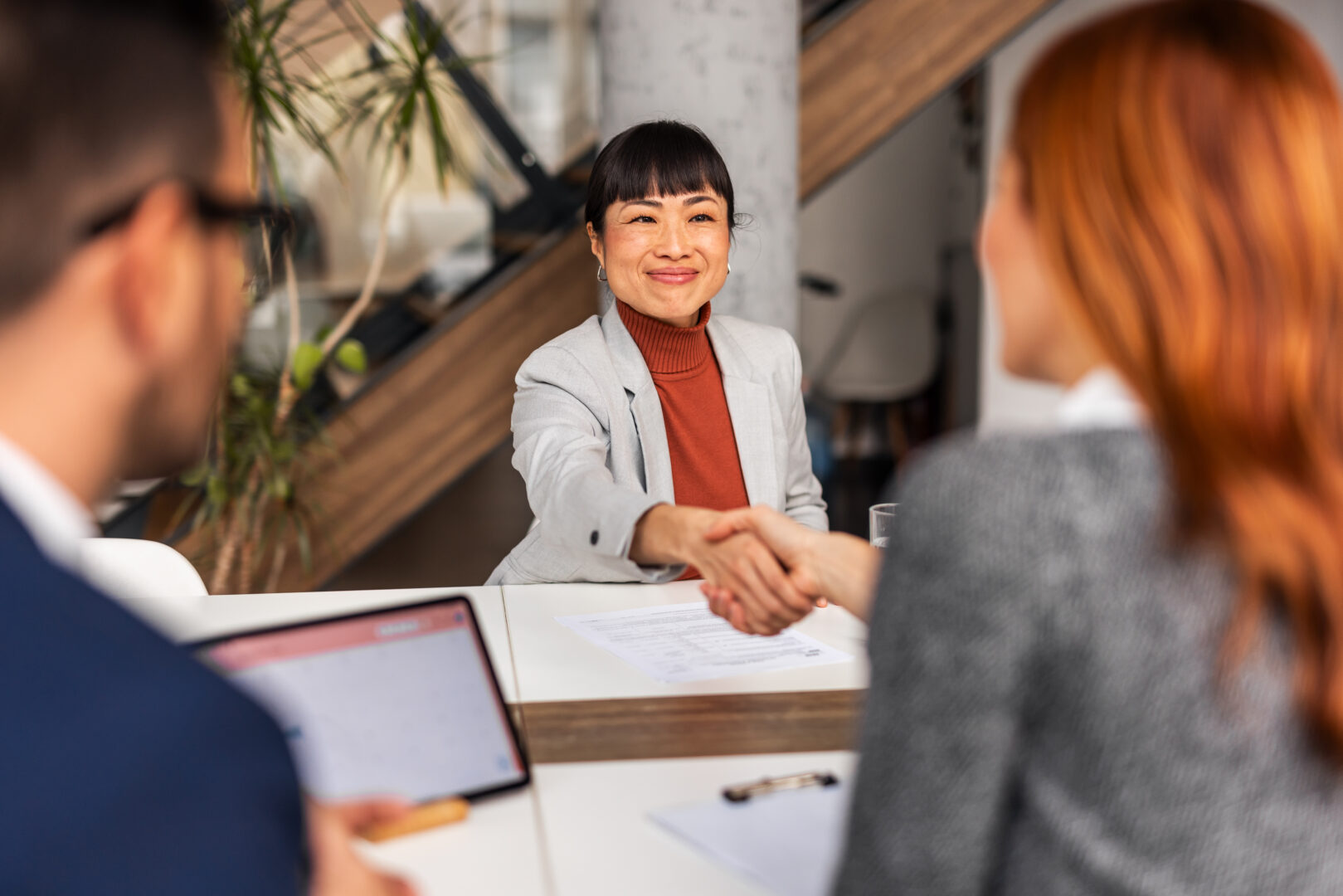 Two people sitting across the table from each other shaking hands